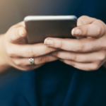 Landesarbeitsgemeinschaft Erziehungsberatung Niedersachsen - Hände, die ein Mobiltelefon halten, Nahaufnahme, Smartphone, Downloads