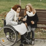 Erziehungsberatung Niedersachsen - Integrative Erziehung - Frau sitzt im Rollstuhl und junges Mädchen zeigt ihr etwas auf dem Smartphone